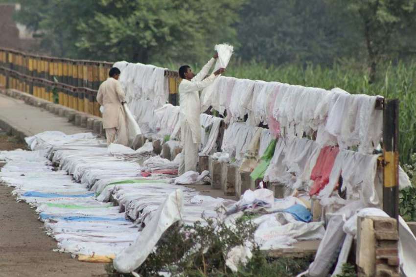 ملتان: مزدور ریلوے پٹریوں کے قریب خشک ہونے کے بعد خالی بیگ ..