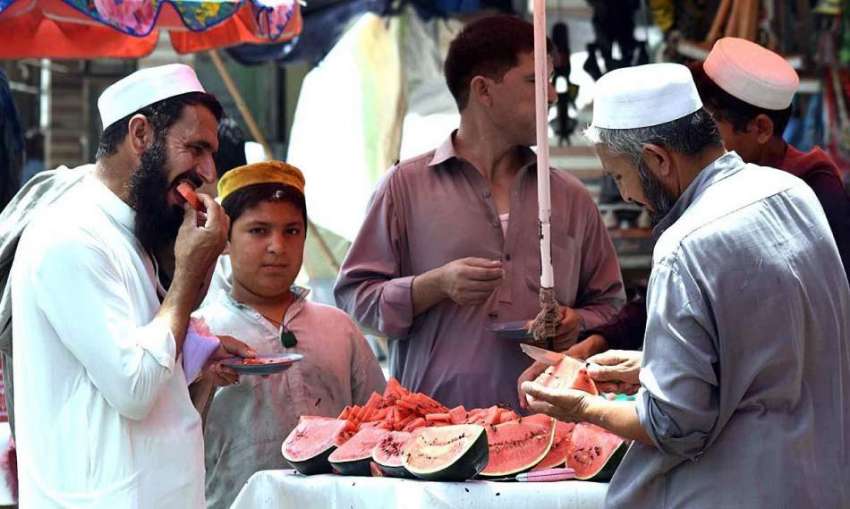 پشاور: شہری ریڑھی بان سے تربوز کھا رہے ہیں۔