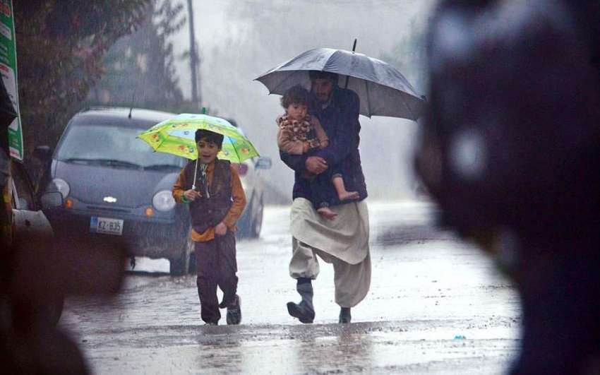 راولپنڈی: شہری بارش سے بچنے کے لیے اپنے بچوں کے ہمراہ چھتری ..
