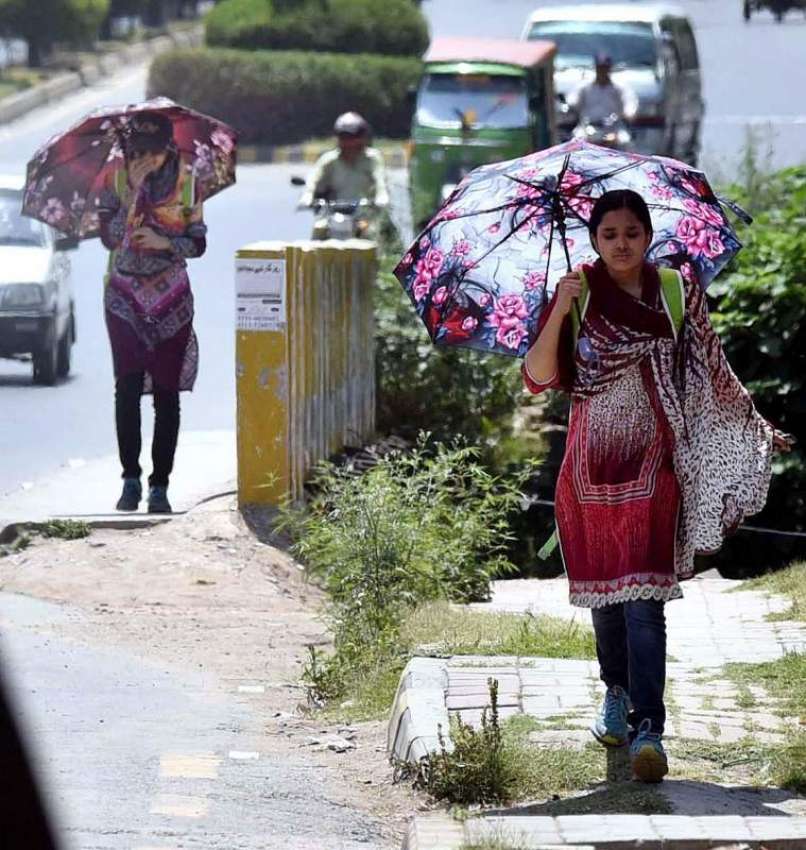راولپنڈی: خواتین دھوپ کی شدت سے بچنے کے لیے چھتری تانے جا ..