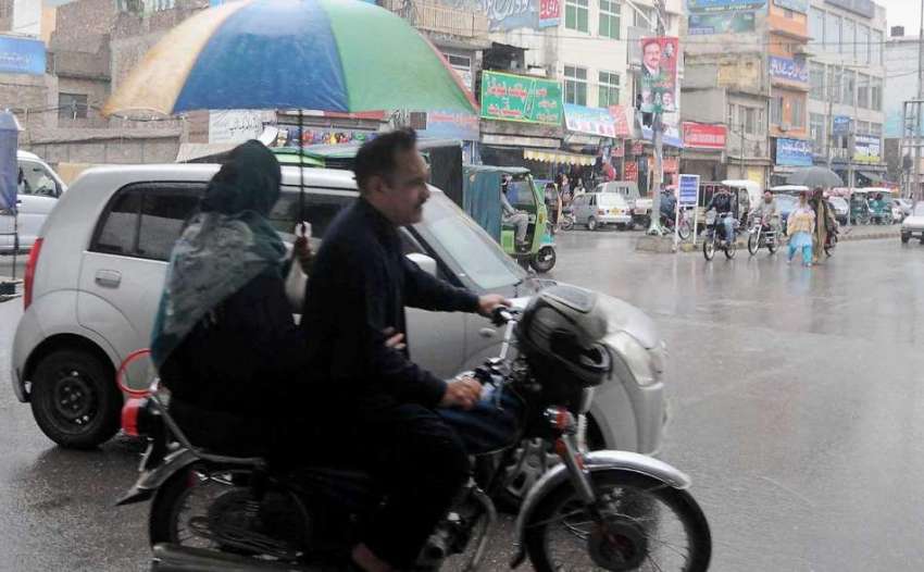 راولپنڈی: موٹر سائیکل سوار فیملی بارش سے بچنے ک لیے چھتری ..