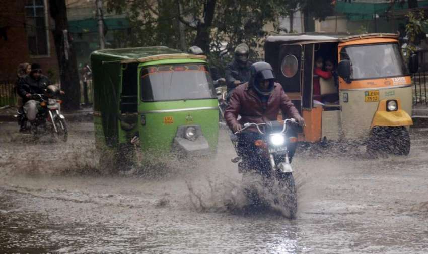 لاہور: موٹر سائیکل سوار بارش کے جمع شدہ پانی سے گزر رہاہے۔