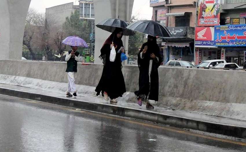 راولپنڈی: خواتین چھتری تانے مری روڈ سے گزر رہی ہیں۔