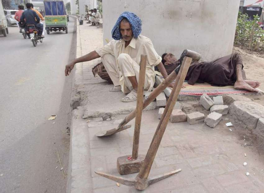لاہور: کام نہ ہونے کے باعث مزدور میٹرو بس کے پل کے نیچے بیٹھے ..