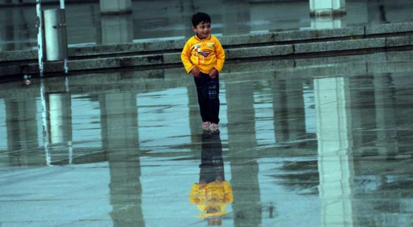 اسلام آباد: ایک بچہ فیصل مسجد کے باہر بارش سے لطف اندوز ہو ..