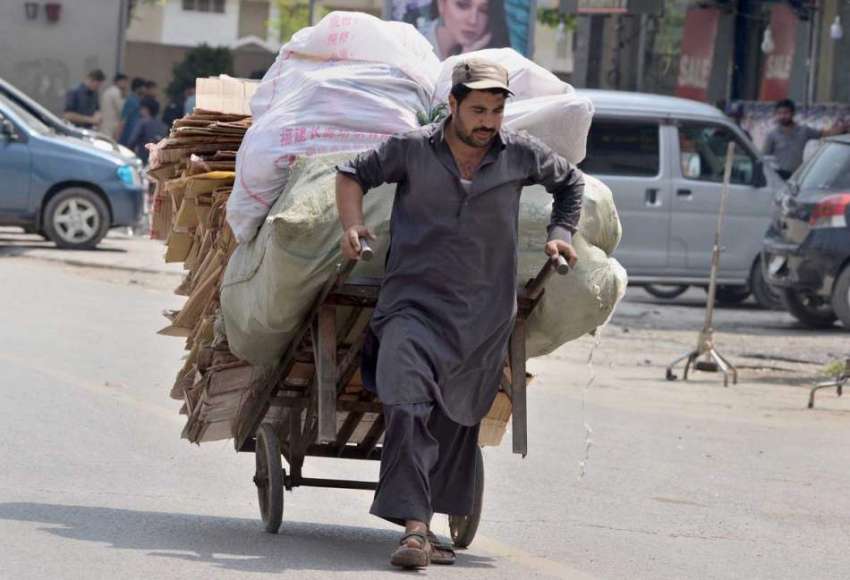 راولپنڈی:ایک محنت کش ہاتھ ریڑھی پر سامان رکھ کر کھینچتا ..