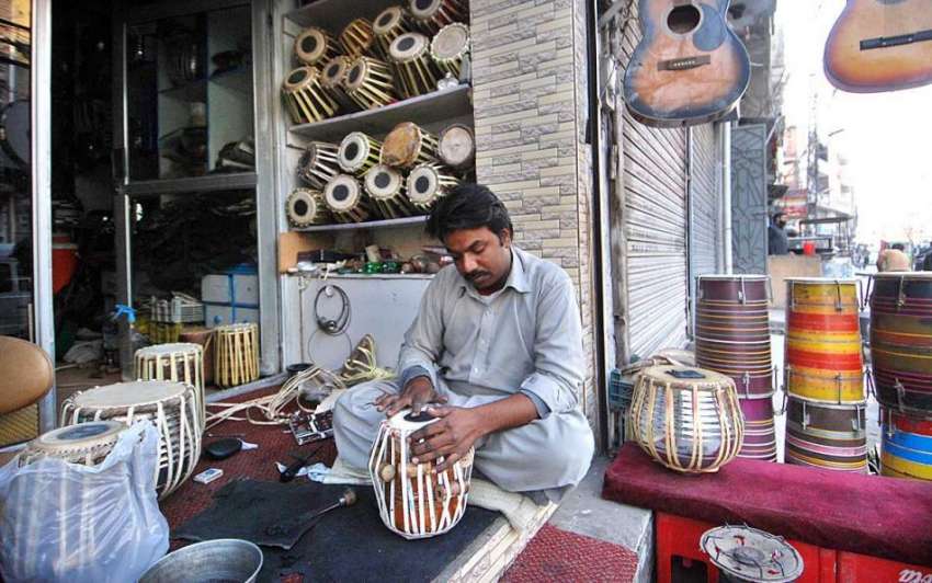 راولپنڈی: ایک دکاندار سڑک کے کنارے میوزک کے آلے ڈھولکی تیار ..