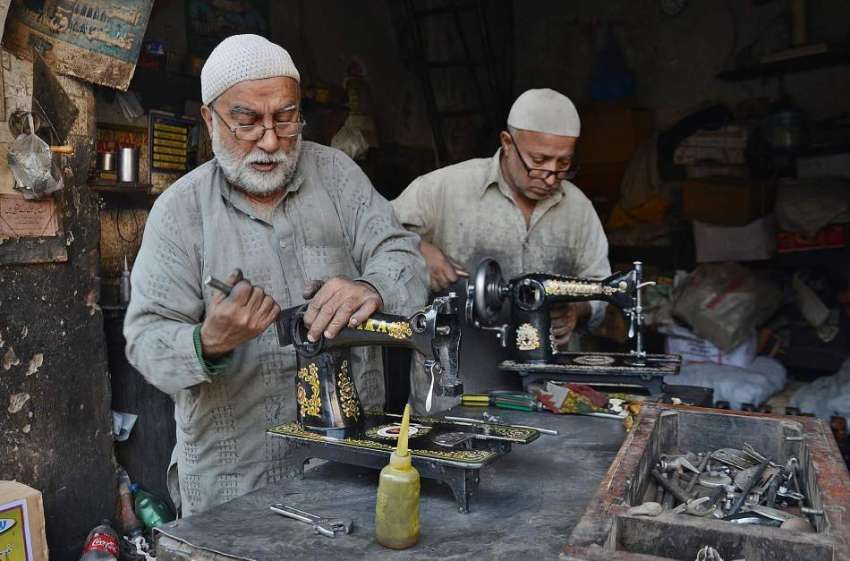 لاہور: محنت کش اپنی ورکشاپ میں سلائی مشینیں مرمت کر رہے ہیں۔