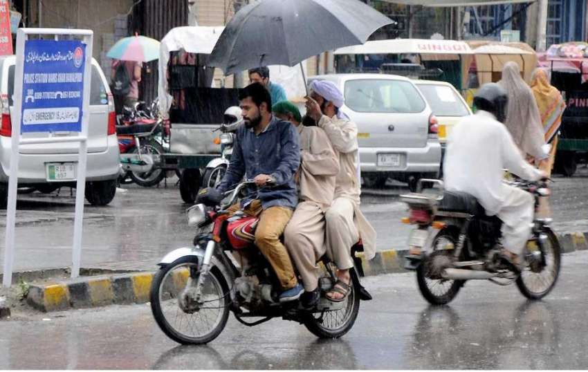را ولپنڈی: موٹر سائیکل سوار بارش سے بچنے کے لیے چھتری تانے ..