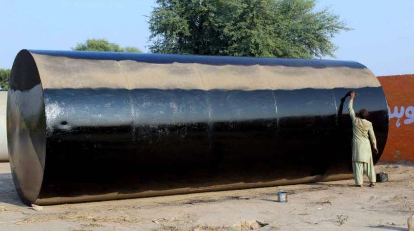 ملتان: ایک پینٹر اپنے کام کی جگہ پر تیل کے بڑے ٹینک کو پینٹ ..