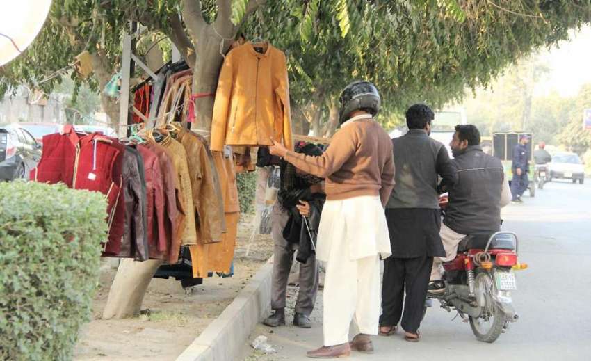 لاہور: شادمان روڈ کنارے شہری جیکٹ خریدنے کے لیے پسند کررہا ..