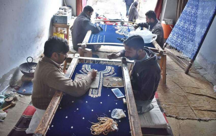 فیصل آباد: محنت کش کپڑے پر کڑھائی کے کام میں مصروف ہیں۔