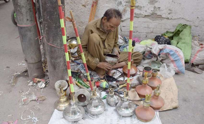 لاہور: اندرون شہر میں ایک محنت کش حقے مرمت کررہاہے۔