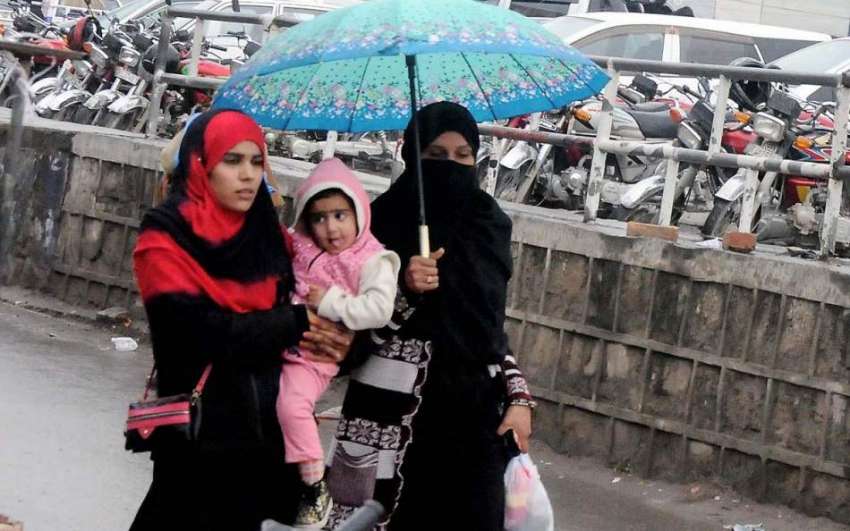 ر اولپنڈی: خواتین نے بارش سے بچنے کے لیے چھتری تان رکھی ہے۔