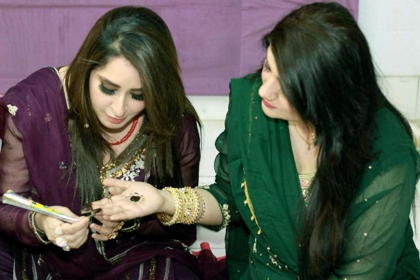 لاہور: ایک خاتون عیدالفطر کی تیاری کے لیے اپنی ساتھ کے ہاتھ ..