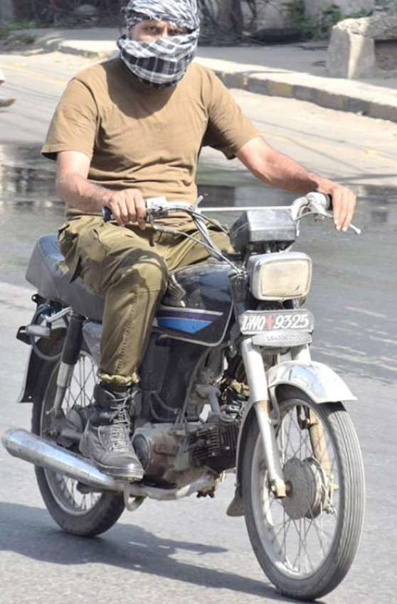 لاہور: ایک موٹر سائیکل سوار پولیس اہلکار گرم لو سے بچنے کے ..