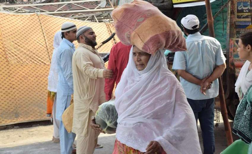 لاہور: ایک خاتون رمضان بازار سے خریدا سامان اپنے سر پر رکھ ..