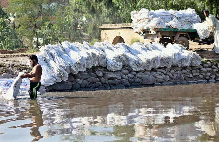 ملتان: نہر میں مزدور خالی بیگ دھونے میں مصروف ہیں۔
