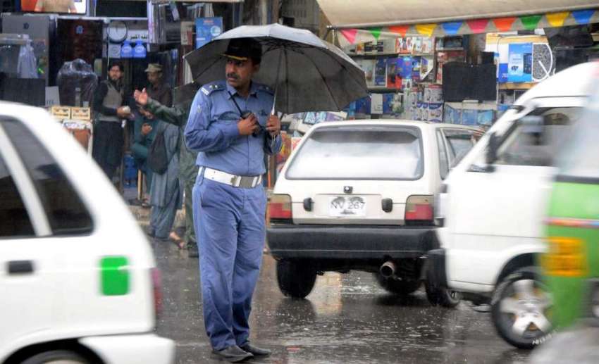 راولپنڈی شہر میں ہونیوالی بارش کے دوران ٹریفک وارڈن چھتری ..