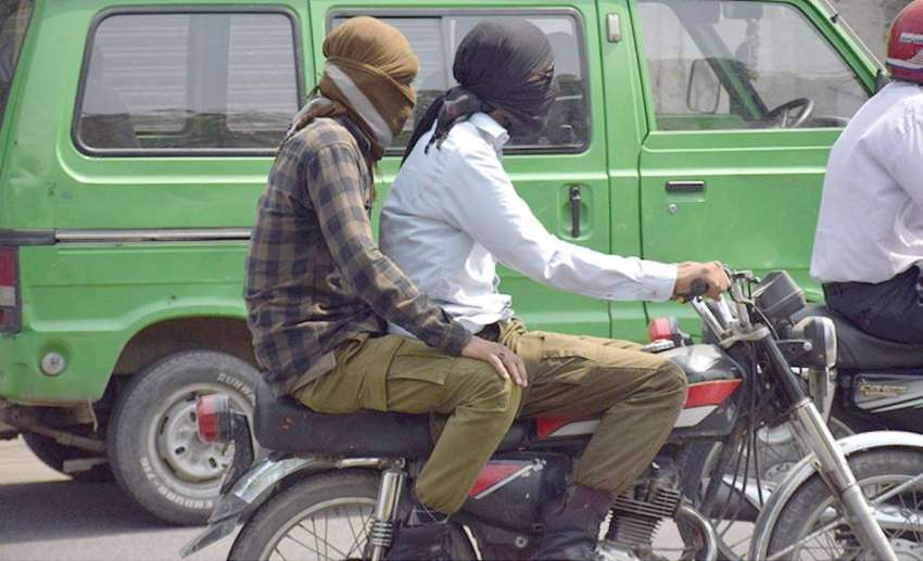 لاہور: ایک موٹر سائیکل سوار پولیس اہلکار گرمی کی شدت سے بچنے ..