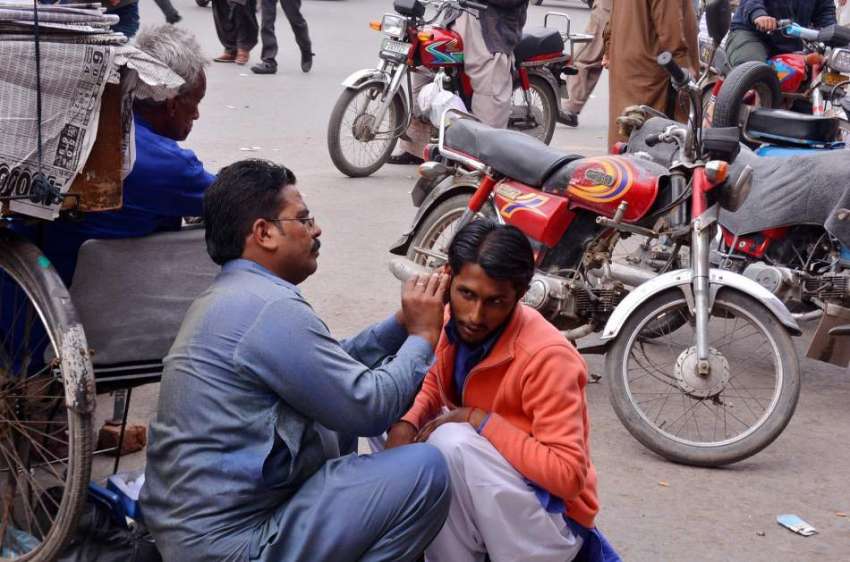 فیصل آباد: ایک شہری اتائی سے اپنے کان کا علاج کروا رہا ہے۔