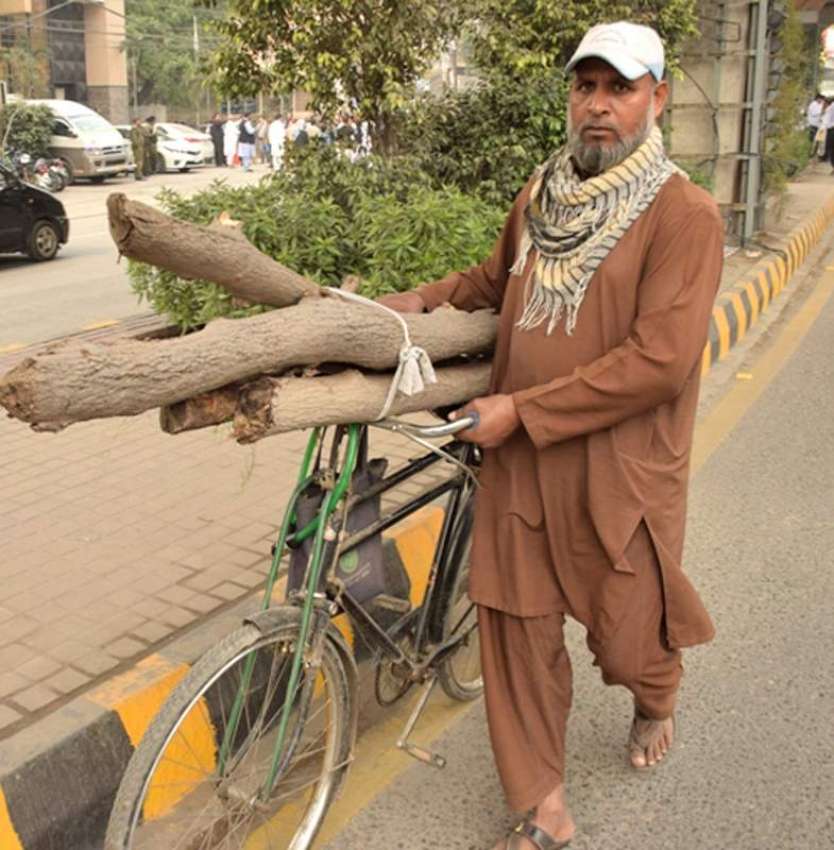 لاہور : ایک شخص جلانے کیلئے لکڑیاں سائیکل پر رکھے جارہا ہے۔ ..