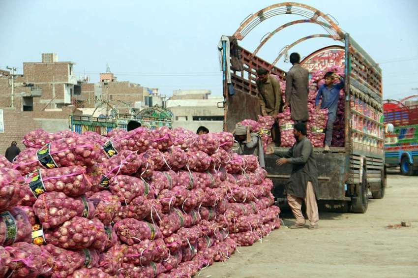 ملتان: سبزی منڈی میں مزدور ڈیلیوری ٹرک سے پیاز کے تھیلے اتارنے ..