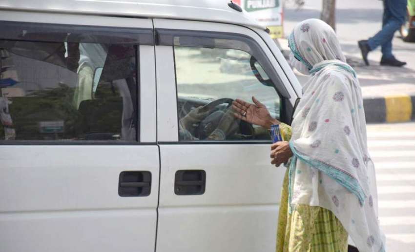 لاہور: ایک بھکاری خاتون گاڑی والے سے بھیک مانگ رہی ہے۔ 
