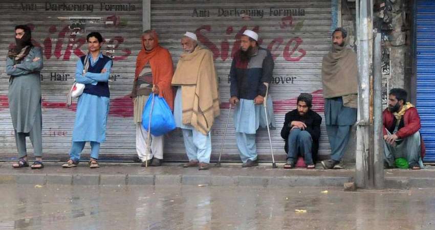 راولپنڈی، بارش کے دوران مزدور مزدوری کی تلاش میں کھڑے ہیں۔