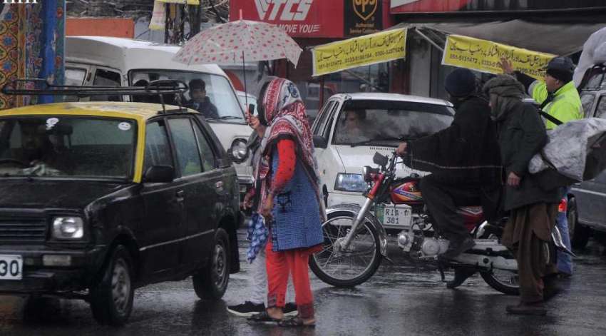 راولپنڈی:خواتین بارش سے بچنے کیلئے چھتری تانے جارہی ہیں ..