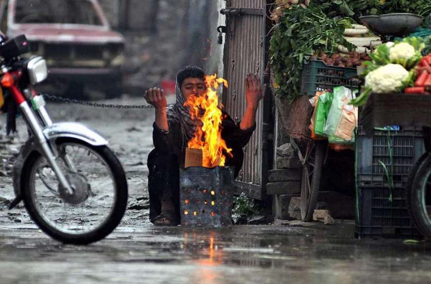 راولپنڈی: ٹھنڈا موسم کے دوران ایک دکاندار  اپنے آپ کو گرم ..