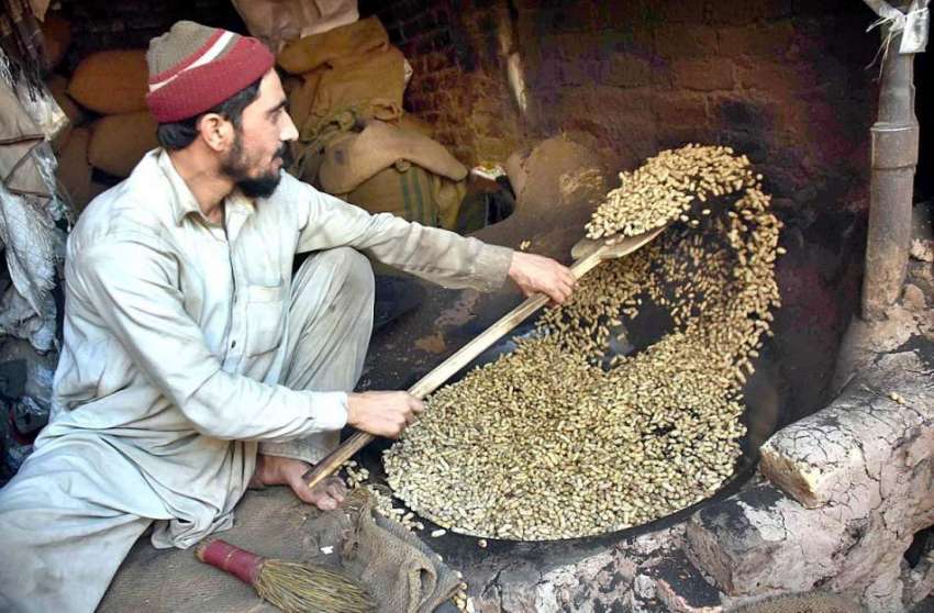 پشاور: ایک مزدور اپنے کام کی جگہ پر مونگ پھلی بھون رہا ہے۔
