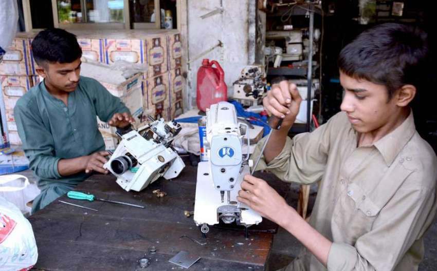 فیصل آباد: اپنے کام کی جگہ پر سلائی مشین ٹھیک کرتے ہوئے کاریگر