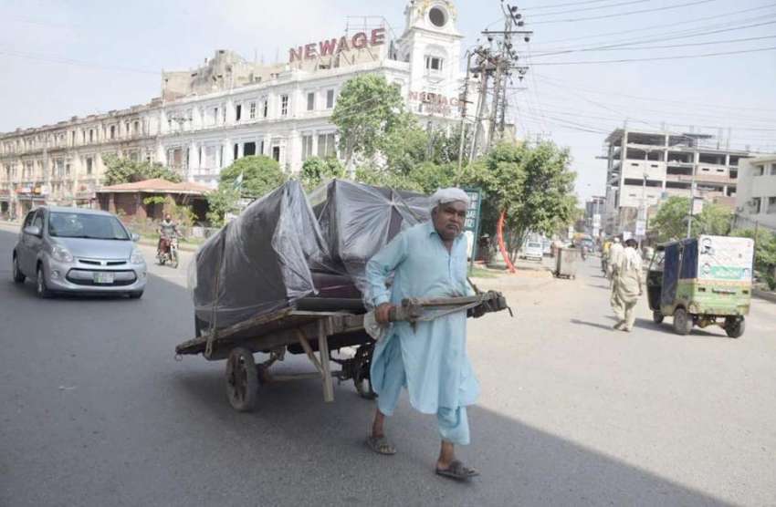 لاہور:ایک محنت کش ہتھ ریڑھی پر بھاری سامان رکھ کر لے جارہا ..