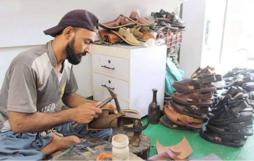 کراچی : مقامی کارخانے میں ایک کاریگر پشاوری چپلیں تیار کر ..