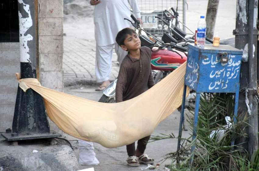 لاہور: ایک بچہ کپڑے سے بنائے گئے جھولے میں اپنے کمسن بھائی ..