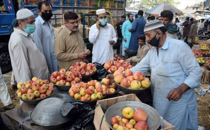 لاہور : مرکزی سبزی منڈی میں شہری دکاندار سے سیب خرید رہے ..