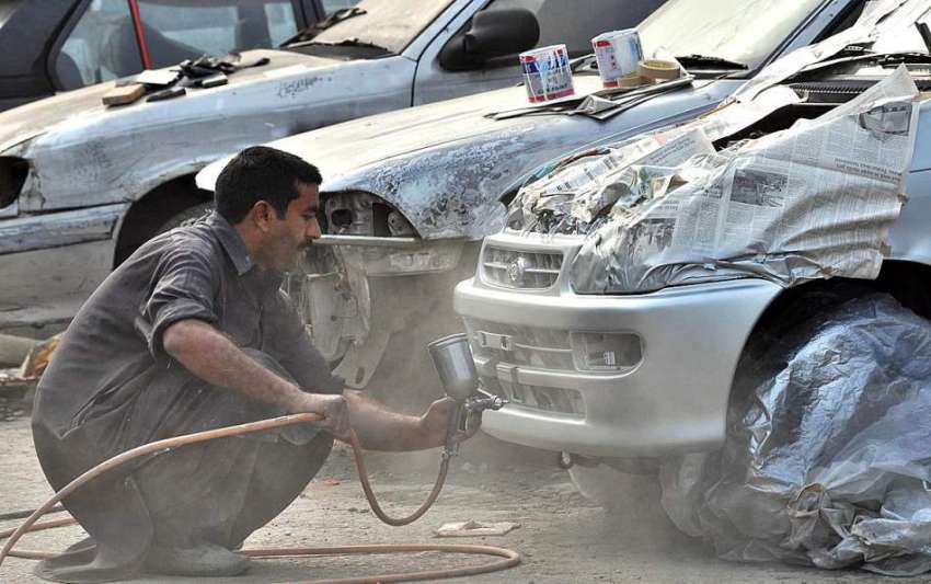 اسلام آباد: ایک پینٹر اپنی ورکشاپ میں گاڑی پینٹ کر رہا ہے۔
