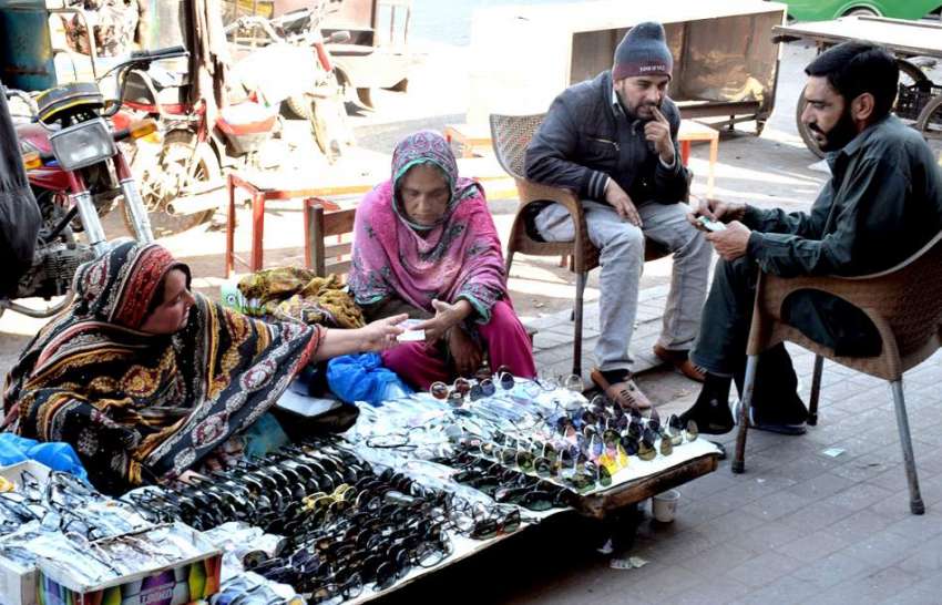 لاہور : ایک خاتون سڑک کنارے لگائے گئے سٹال سے چشمه خرید رہی ..
