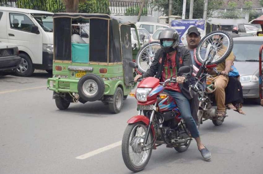 لاہور : موٹرسائیکل سوار سائیکل رکھ کر لے جارہے ہیں۔ 