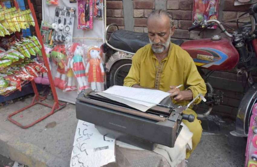 لاہور: ایک محنت کش پرانے دور کی ٹائپ رائٹر مشین پر کام میں ..