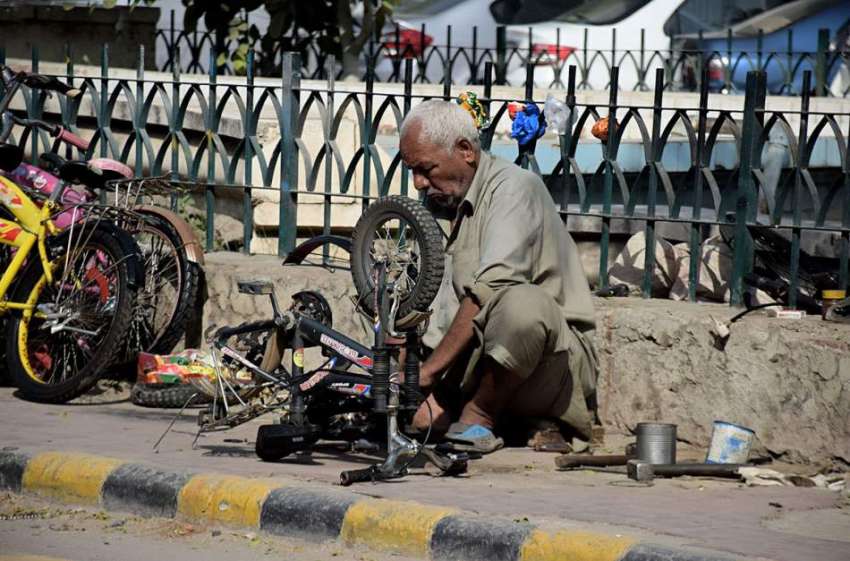 لاہور : نیلا گنبد چوک میں ایک کاریگرسائیکل مرمت کررہا ہے۔