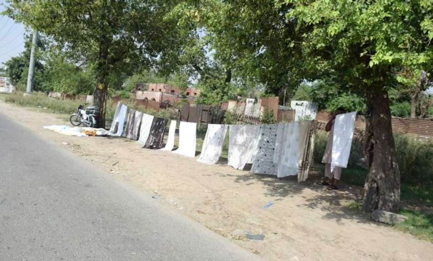 لاہور: ایک شخص نے سڑک کنارے پردے کی چادریں فروخت کرنے کیلئے ..