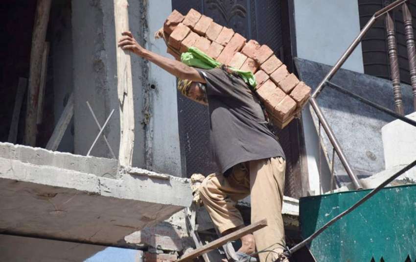 لاہور : مزدور اینٹیں اپنی کمر پرلا د کر بالائی منزل پر لے ..
