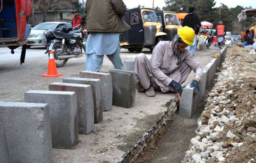 کوئٹہ: ایک مزدور سڑک کے کنارے سیمنٹ والے بلاکس کو ٹھیک کرنے ..