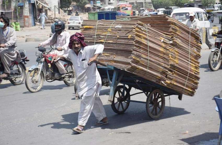 لاہور: ایک محنت کش ہتھ ریڑھی گتے رکھ کر لے جارہا ہے۔