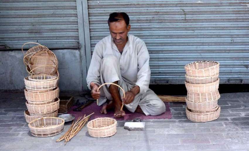 لاہور : ایک دکاندار ہاتھ سے لکڑی کی ٹوکری بنانے میں مصروف ..