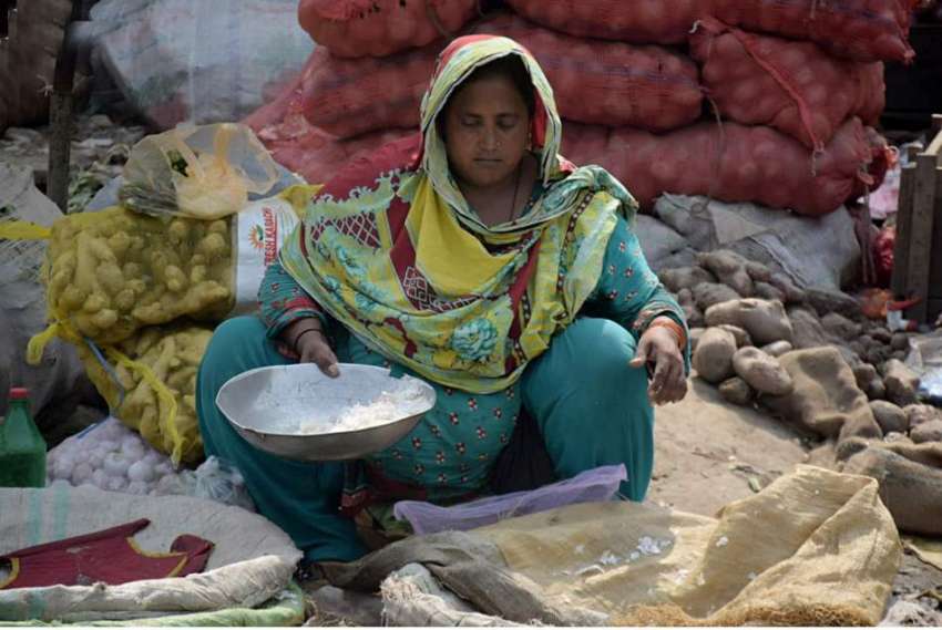لاہور: سبزی منڈی میں ایک محنت کش خاتون لہسن فروخت کر رہی ..
