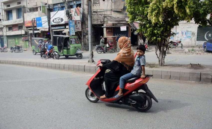 لاہور: ایک خاتون سکوٹی پراپنے بچے کو بٹھائے جارہی ہے۔