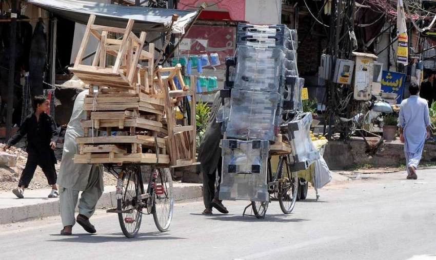 راولپنڈی محنت کش سائیکل پر بھاری سامان لادے رواں دواں ہیں۔ ..